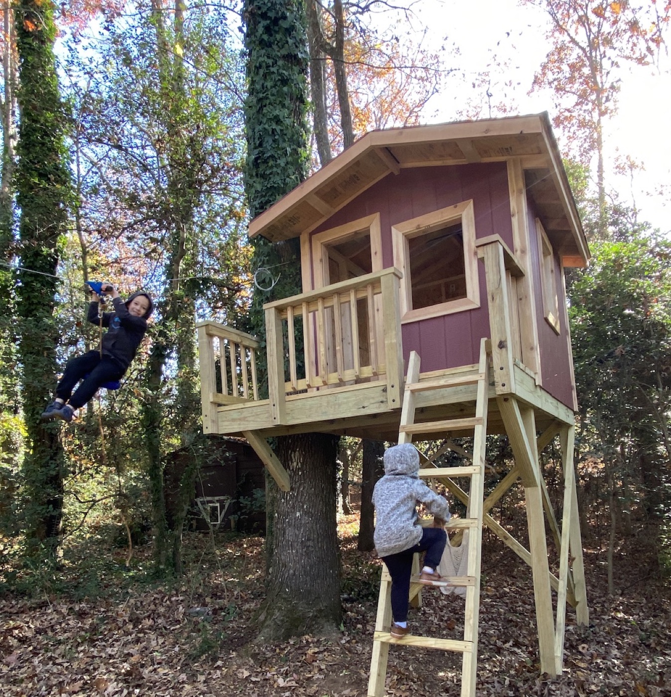 Completed treehouse with siding, windows, and staircase